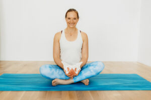 Ursula sitzt mit Beckenboden-Modell auf ihrer Matte